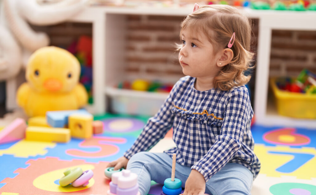 Hispanic girl playing with toys on floor