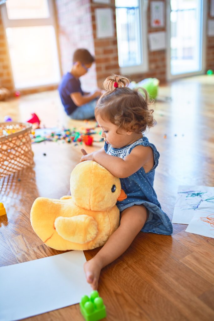 Girl sitting on the floor playing with lots of toys